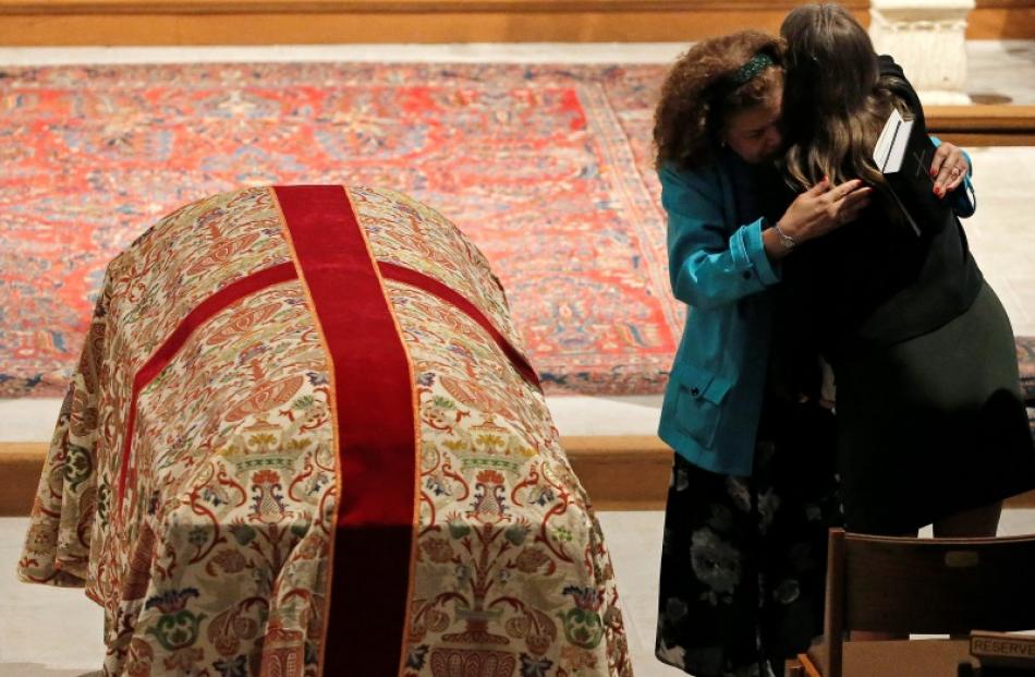 A mourner hugs Christine Leinonen (right), the mother of Christopher Leinonen who died in the...