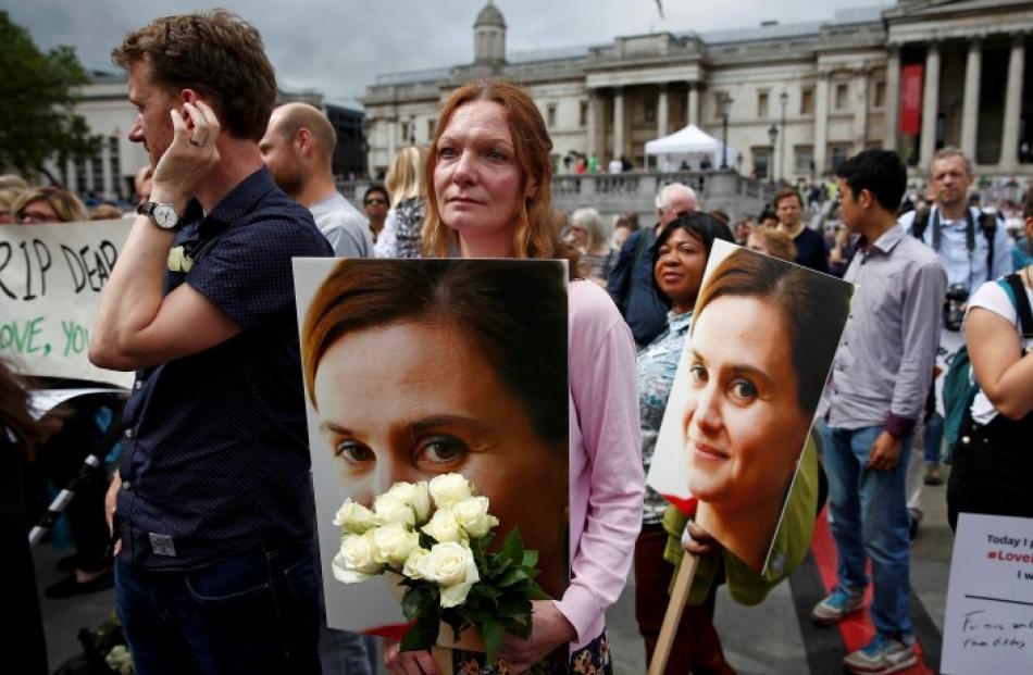 A woman holds a placard and white roses during the service for Jo Cox at Trafalgar Square in...