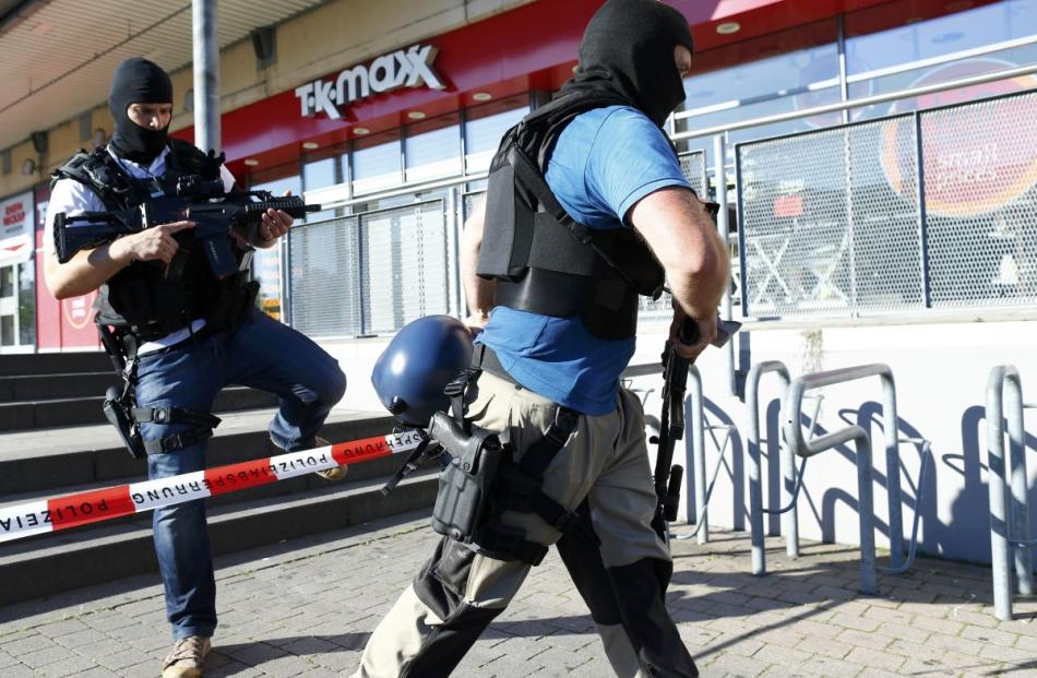 German special police walks past a cinema complex after a masked man with a gun and ammunition...