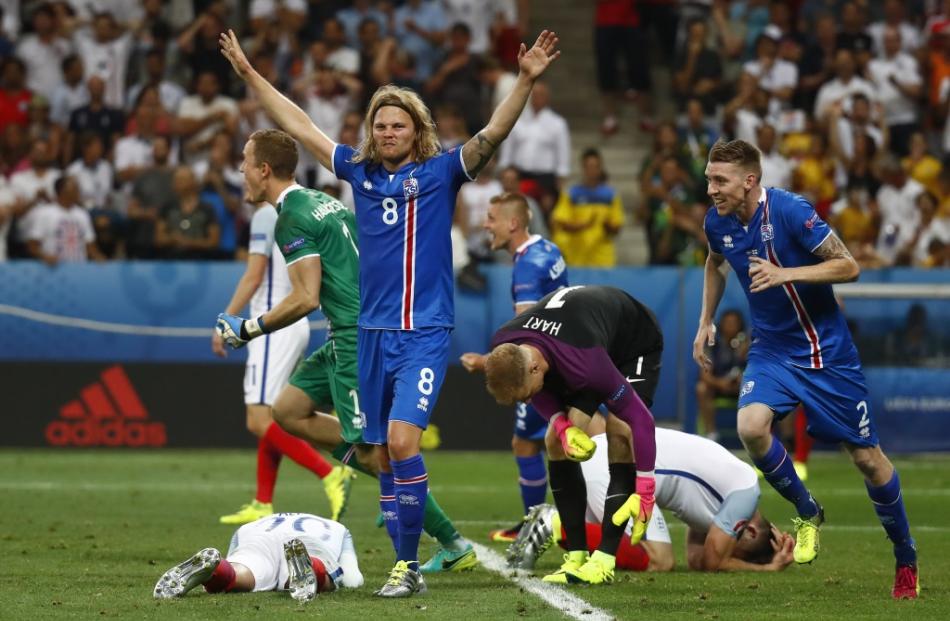 Iceland's Birkir Bjarnason celebrates as England's Joe Hart and Gary Cahill react after the game....