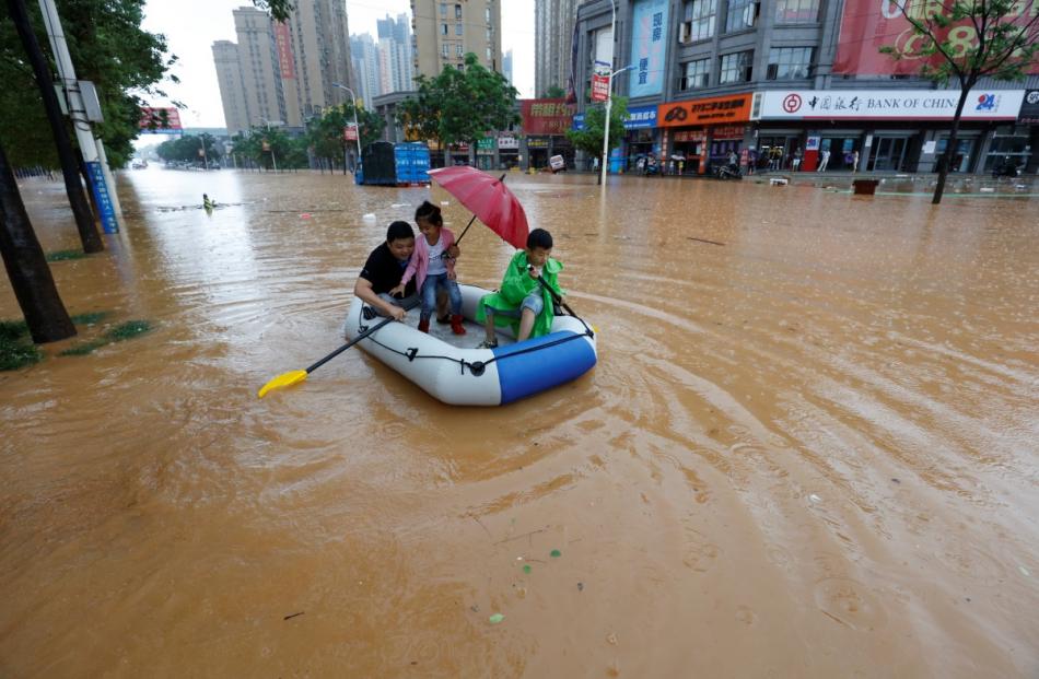 Residents make their way with an inflatable boat through a flooded area in Jiujiang, Jiangxi...