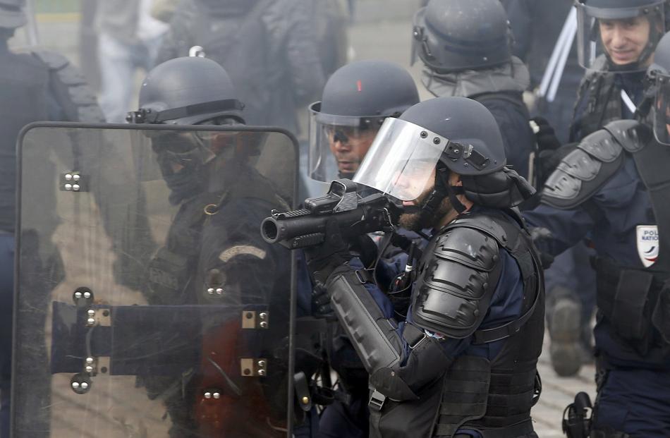 Police take cover behind a riot shield in Paris during a demonstration against French labour law...