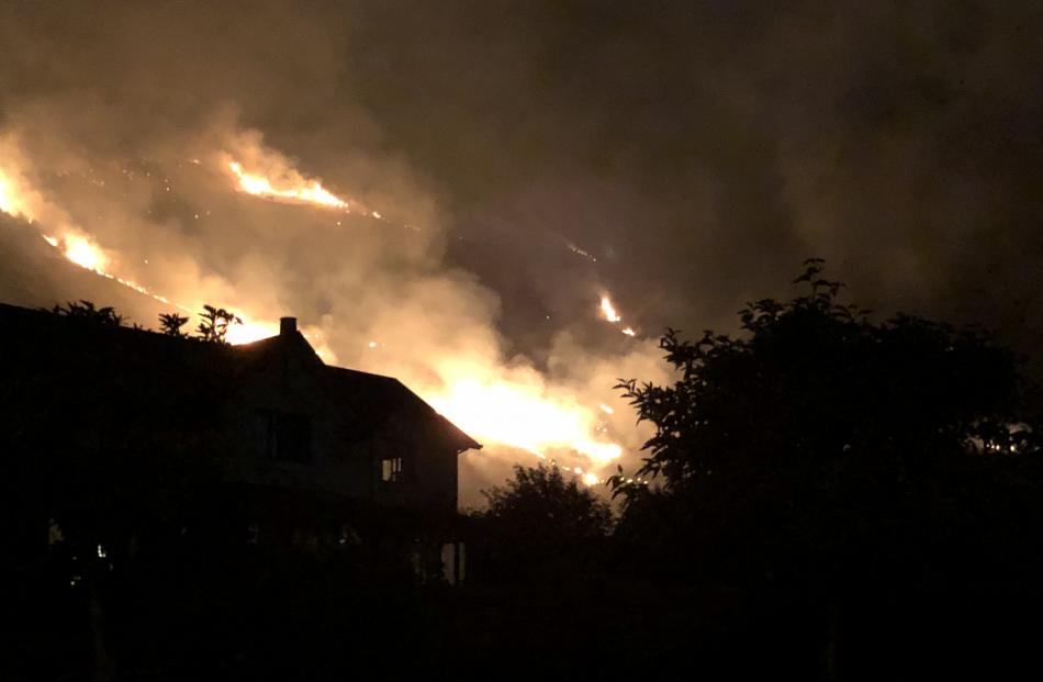 Flames burn near a house in Wanaka last night. Photo: Cameron Romeril