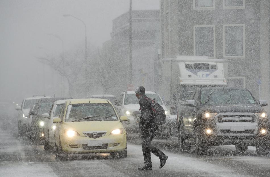 A pedestrian crosses Castle St, in Dunedin, during a heavy snow flurry yesterday morning. PHOTO:...