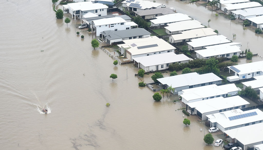 A boat motors along a flooded road in Townsville. Photo: Getty Images